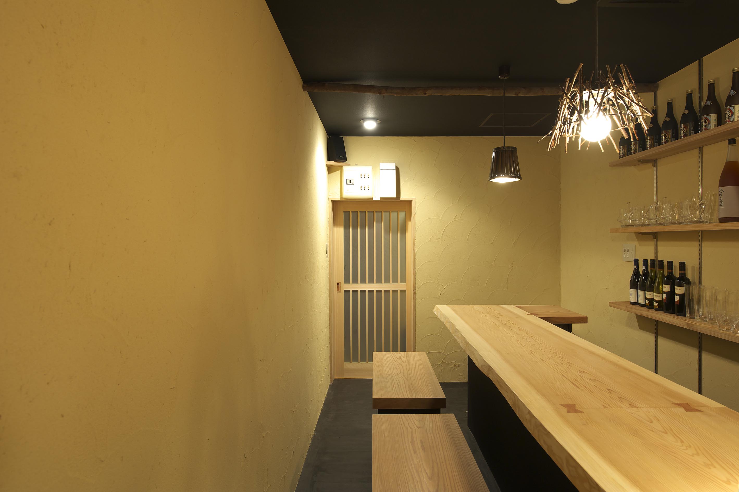 奥から見たヒノキカウンターと珪藻土壁の和風BAR（大阪市中央区）